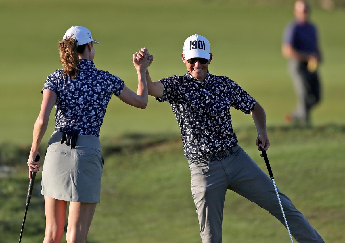 Geoff Cochrane gives teammate Diane Booth a high-five after she sank a long putt for the Santa Ana Country Club team.