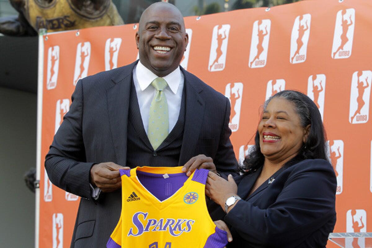 Magic Johnson joins WNBA President Laurel Richie for photos during a news conference to announce new ownership for the francise.