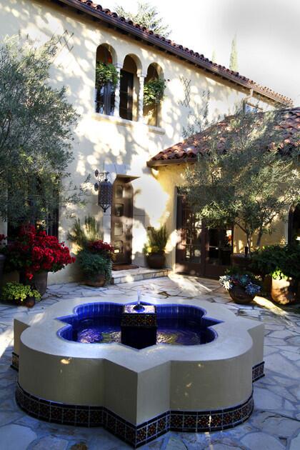 At the top of the stairs, Daigre laid out flagstone and shrank the oversized patio with plenty of comfortable seating and containers of greenery. The centerpiece of the courtyard-like space is a quatrefoil fountain whose gentle splash fills the air with tranquil sound.