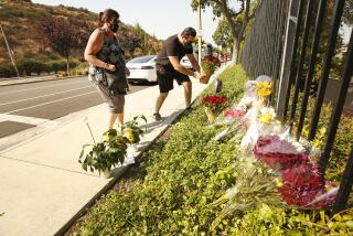 WESTLAKE VILLAGE, CA - SEPTEMBER 30: Lorraine Maralian and her son Anthony Maralian of Westlake Village place flowers and pray at a growing memorial for two brothers who were fatally injured while crossing Triunfo Canyon Road at Saddle Mountain Drive in their Westlake Village neighborhood with their family at 7:10 pm Tuesday evening. Rebecca Grossman, 57, a co-founder of the Grossman Burn Foundation was arrested on two counts of vehicular manslaughter in the death of the two juvenile pedestrians that were in the crosswalk and is being held on $2 million bail. Westlake Village on Wednesday, Sept. 30, 2020 in Westlake Village, CA. (Al Seib / Los Angeles Times