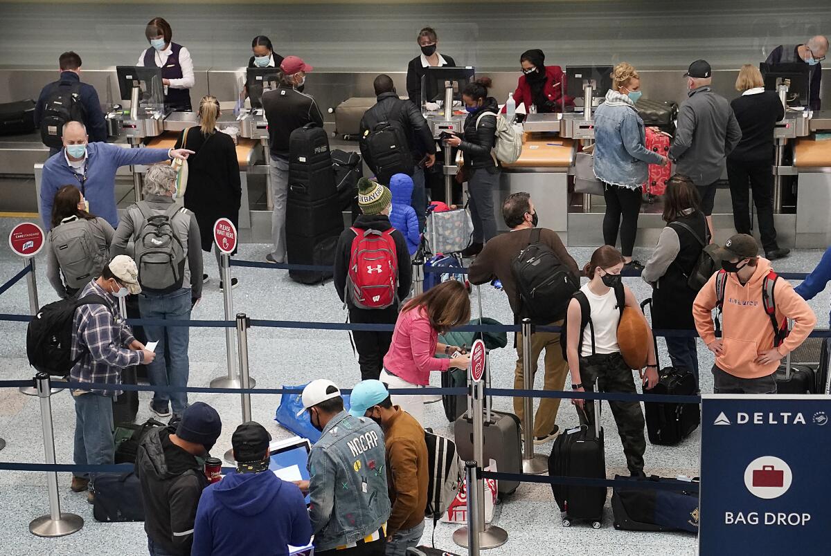 Travelers in a line in front of ticketing workers at an airport