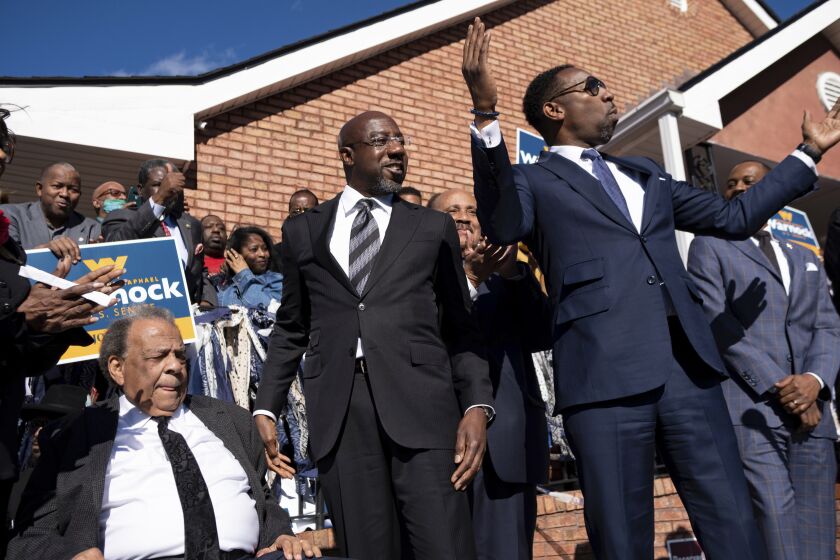 Sen. Raphael Warnock, D-Ga., center, prepares to speak at a rally after being introduced by Civil Rights icon Andrew Young, left, and Atlanta Mayor Andre Dickens on Sunday, Nov. 27, 2022, in Atlanta. (AP Photo/Ben Gray)