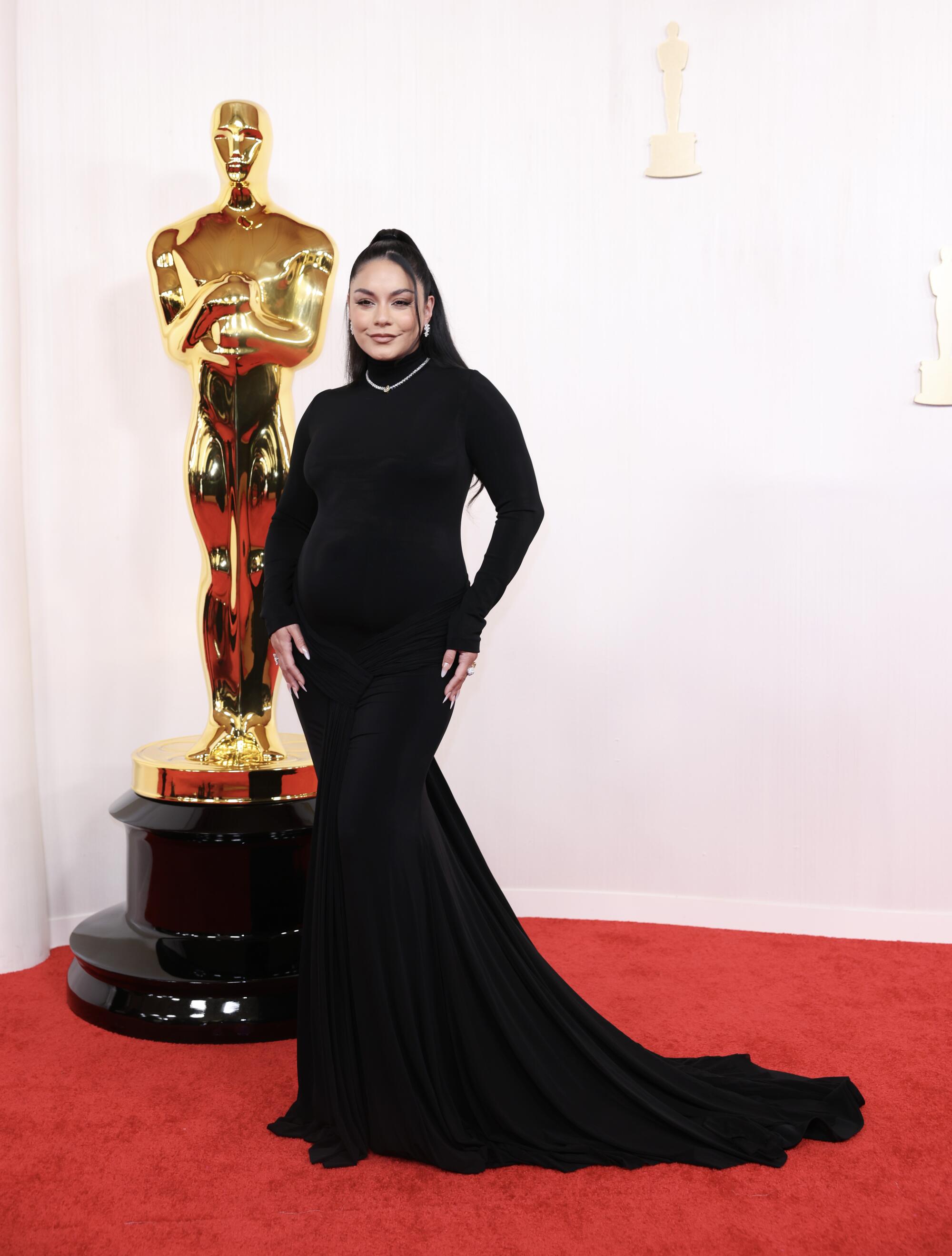 A pregnant Vanessa Hudgens wears a form-fitting black dress.