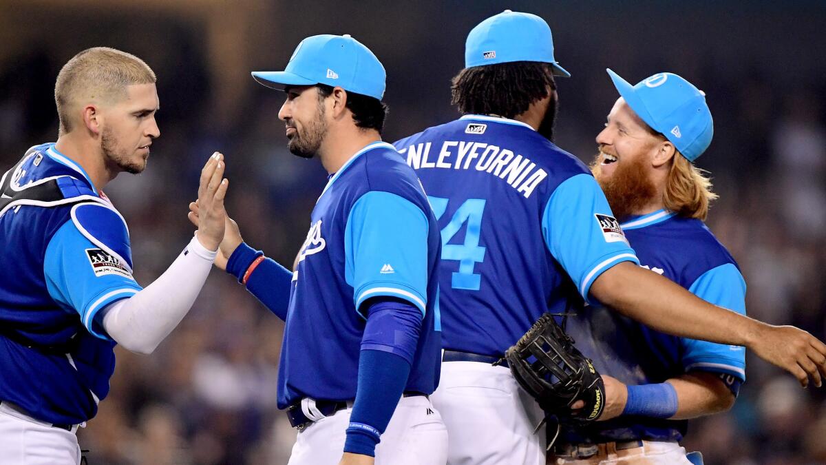 Dodgers players, wearing uniforms inspired by youth leagues, celebrate after a victory over the Brewers.