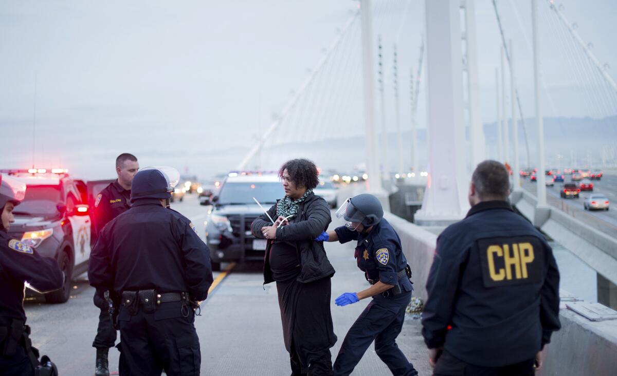 A California Highway Patrol officer detains a protester on the San Francisco-Oakland Bay Bridge. (Noah Berger / Associated Press)