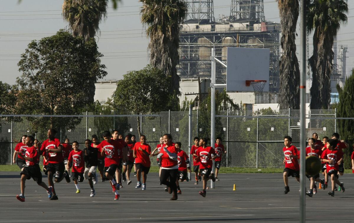 Students jog on the playground at Elizabeth Hudson K-8 Elementary School in Long Beach. The school sits near the Tesoro oil refinery, the Terminal Island Freeway, a railroad line and the Port of Long Beach. (Don Bartletti / Los Angeles Times)