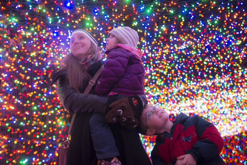 Sarah Johnson holds 2-year-old Samantha as Philip, 5, stands alongside in the light tunnel at Zoolights in Oregon Zoo.