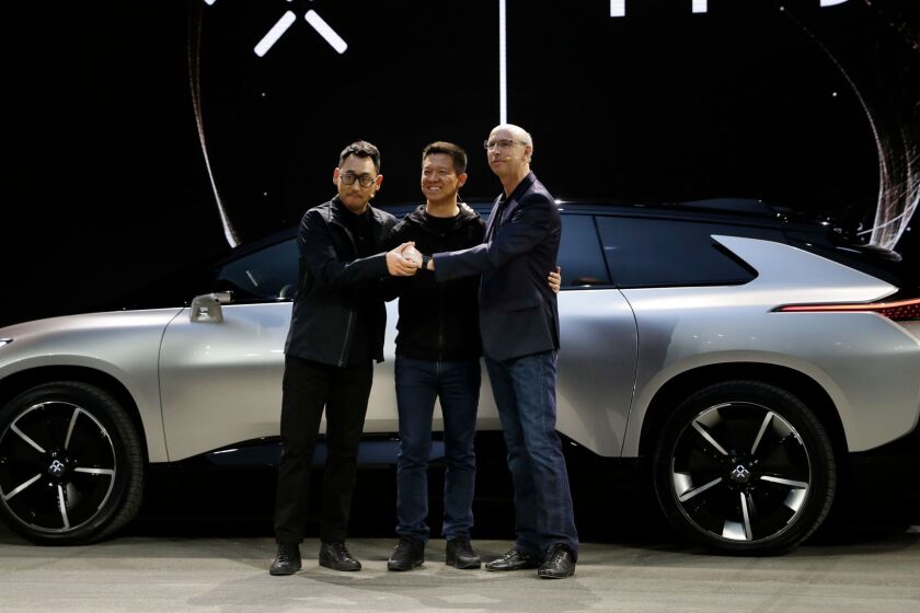 LeEco CEO YT Jia, center, poses with Nick Sampson, Faraday Future's senior vice president of product research & development, right, and Richard Kim, vice president of design, after unveiling the FF91 electric car at CES International Tuesday, Jan. 3, 2017, in Las Vegas. (AP Photo/Jae C. Hong)