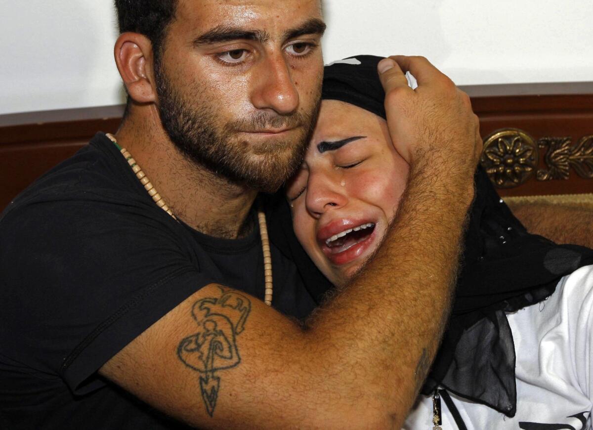 Fatima, the daughter of slain Syrian political analyst Mohammad Darrar Jammo, grieves in the comfort of a relative.