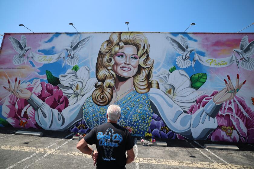 Costa Mesa, CA - Aug. 26, 2026: Jeff Weiss, of Costa Mesa, who has been a lifetime Dolly Parton fan, views a Dolly Parton mural at 719 W. 19th St. in Costa Mesa on Wednesday, Aug. 26, 2026. "She did a lot of good for everyone," Weiss said. "She didn't think about herself, she thought about other people." (Allen J. Schaben / Los Angeles Times)