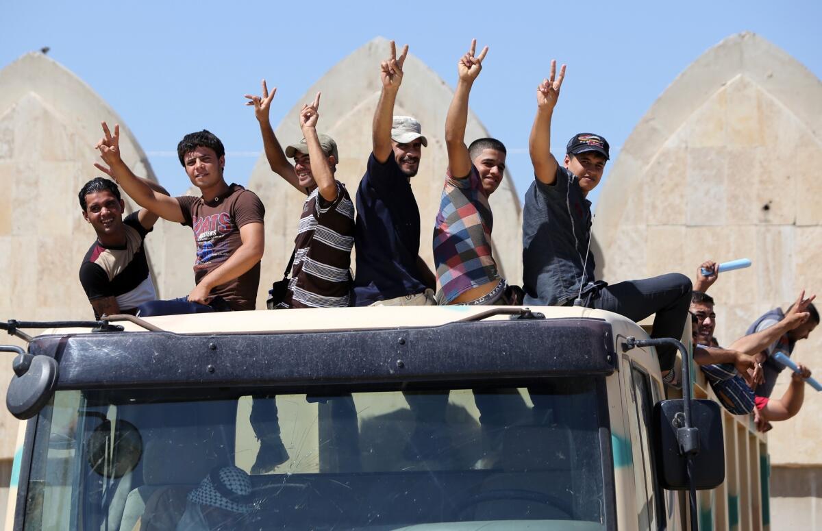 Iraqi volunteers fighting alongside the country's security forces against Islamist militants flash the victory sign as they leave a recruitment center in Baghdad.