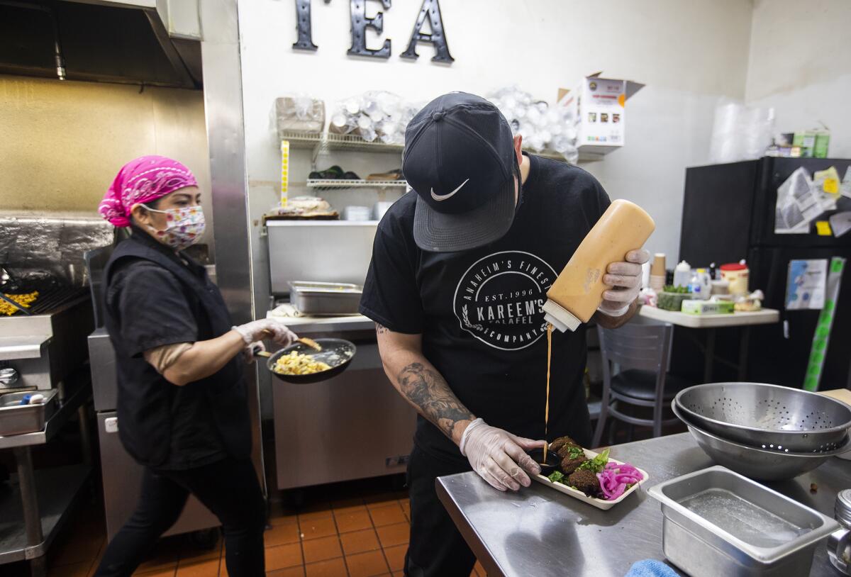 Kareem Hawari, owner of Kareem's Falafel in Anaheim, pours chipotle tahini into a serving container.