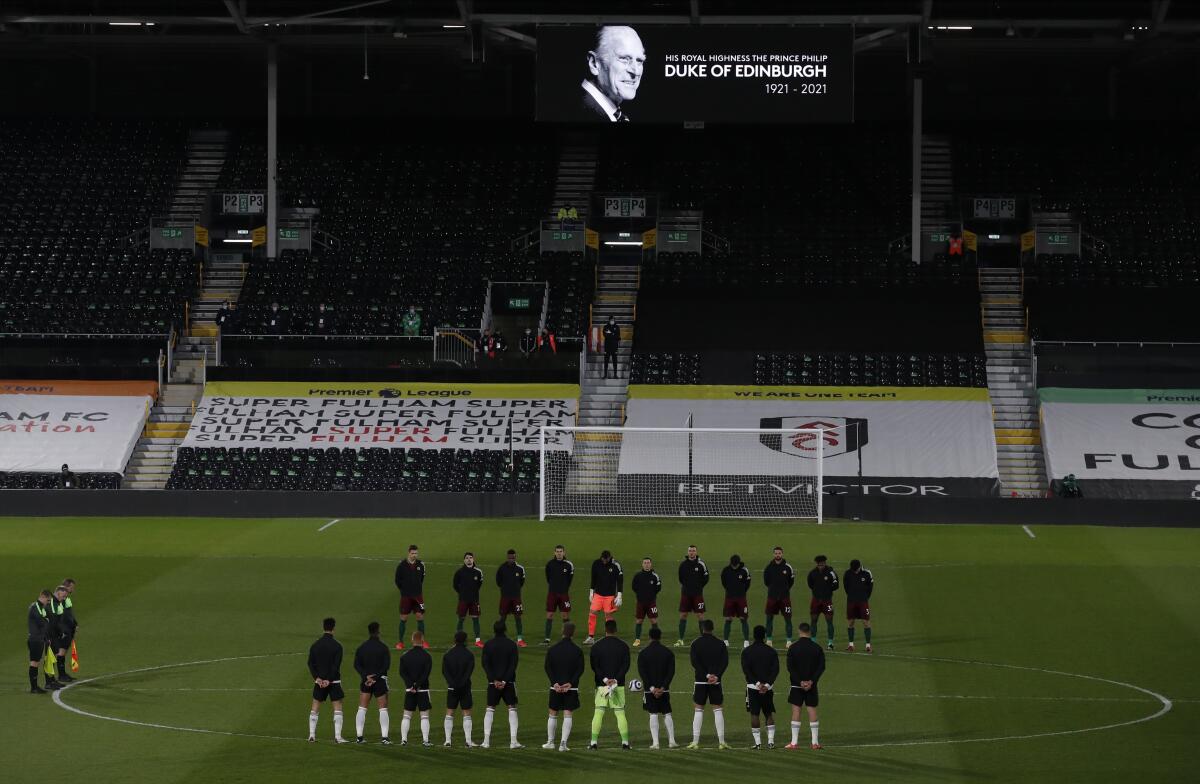 Players from both sides observe a minute's silence to honor Britain's Prince Philip, Duke of Edinburgh, after the announcement of the death today, before the English Premier League soccer match between Fulham and Wolverhampton Wanderers at Craven Cottage stadium in London, England, Friday, April 9, 2021.(Andrew Couldridge/Pool via AP)