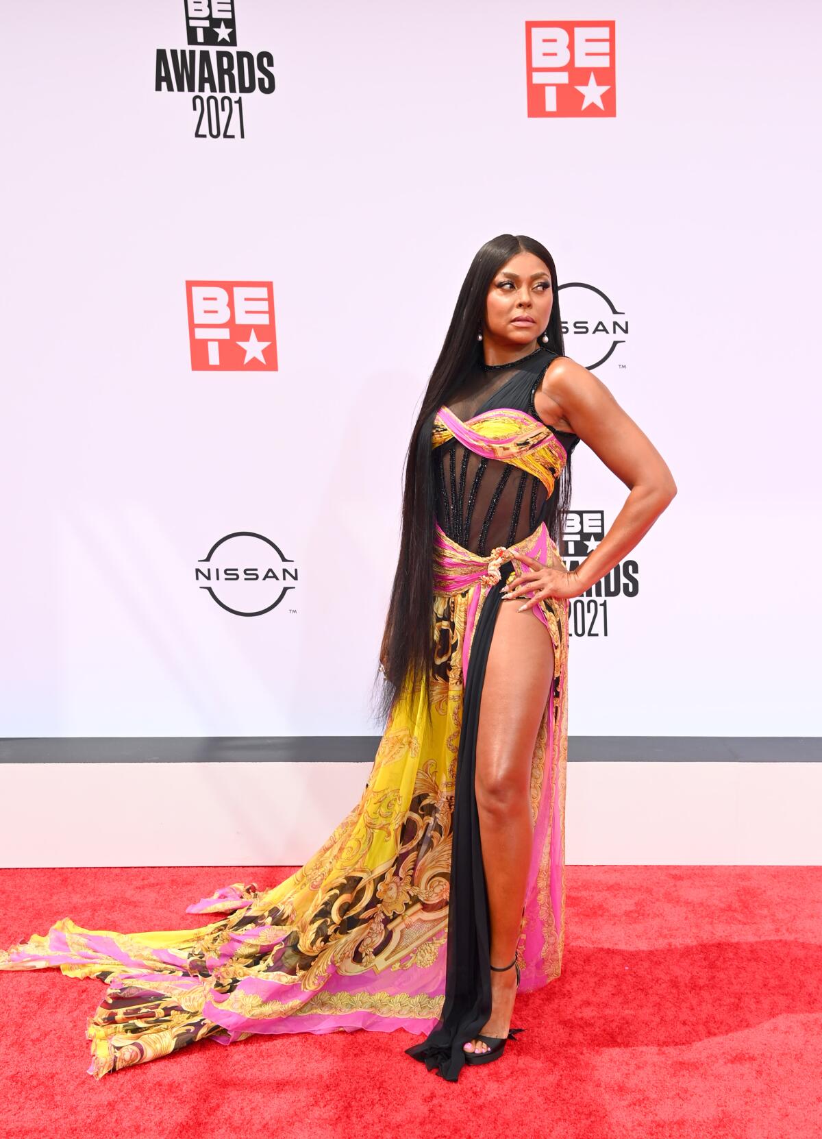 A woman in black, yellow and pink formal attire with a high slit showing her leg