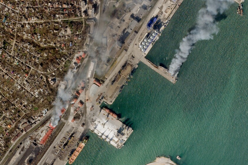 An aerial view shows a Ukrainian naval vessel and a nearby building burning.