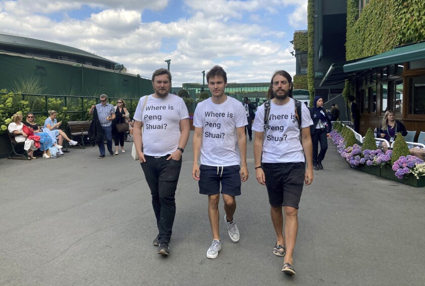 From left Protesters Will Hoyles, 39, Caleb Compton, 27, and Jason Leith, 34, who all work for Free Tibet pose for the media in T-shirts reading "Where is Peng Shuai", at the Wimbledon Tennis tournament in London, Monday, July 4, 2022. Four activists wearing “Where is Peng Shuai?” T-shirts were stopped by security at Wimbledon on Monday and had their bags searched. (Rebecca Speare-Cole/PA via AP)