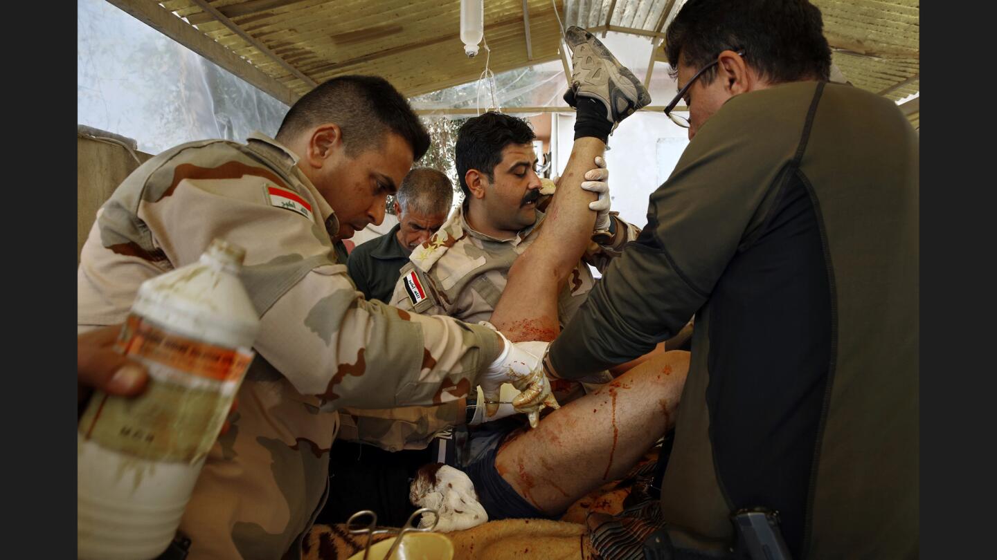 At the Iraqi army’s 9th Armored Division medical clinic, doctors Major Mohammed Hassan Abdullah, from left, Captain Osama Fuad Rauf and Maj. Gen. Raad Mohssan Dakhel work together on a soldier who was shot by an Islamic State sniper.