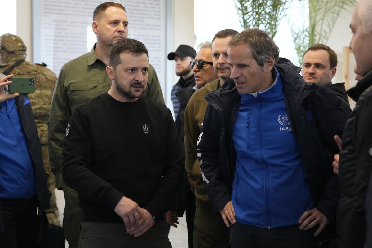 Volodymyr Zelensky, left, stands with Rafael Mariano Grossi in a group of men