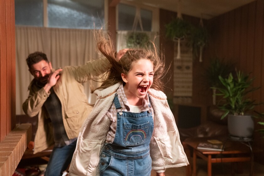A little girl releases a hair-raising scream as a man recoils behind her in the movie “Firestarter.”