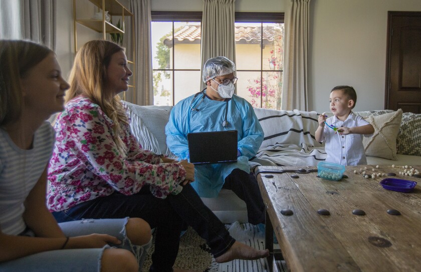 Dr. Ashish Bhalla, center, talks with Gage Hernadez during an in-home doctor visit.