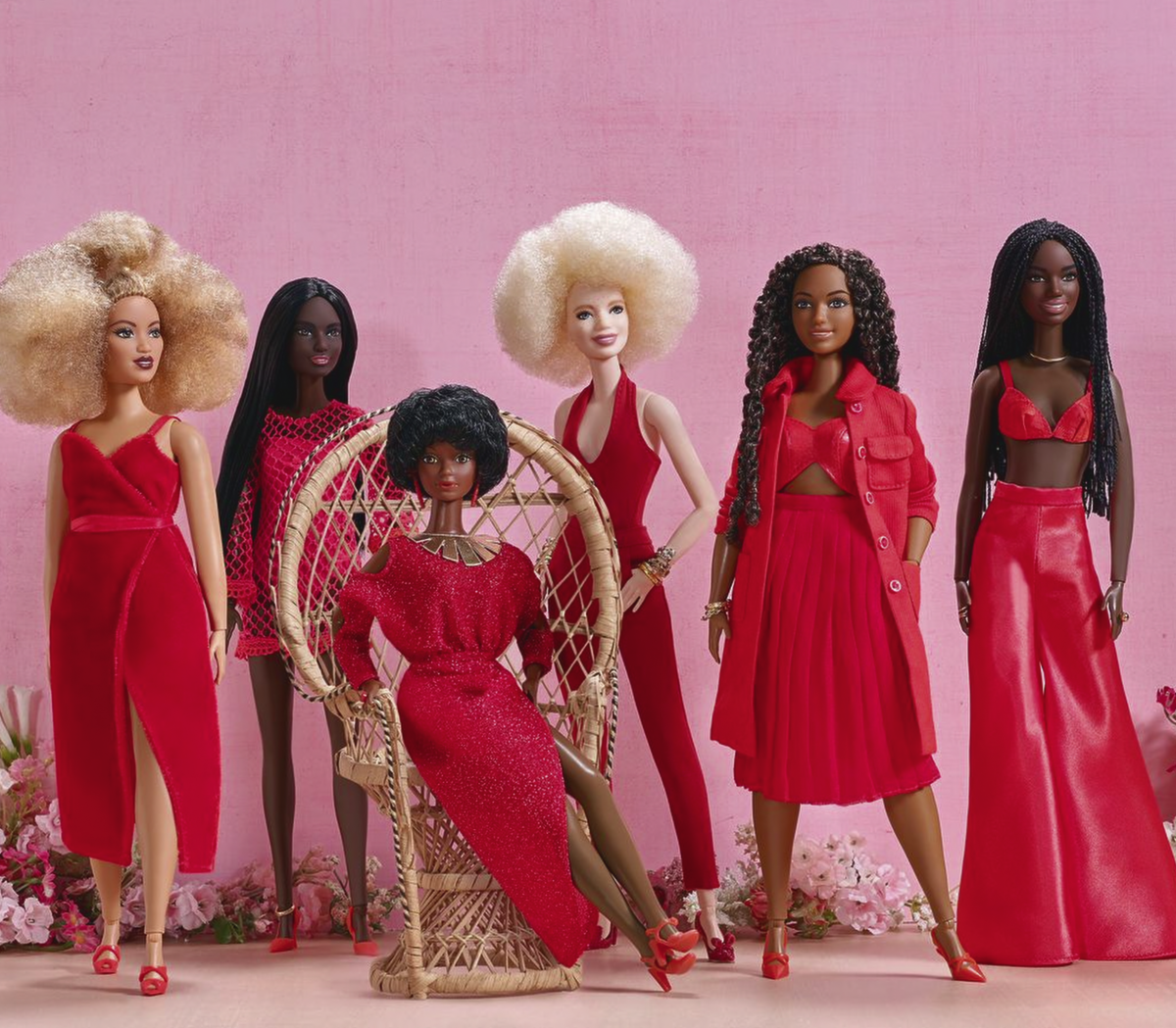 Black Barbie dolls of different skin tones wearing different red outfits.
