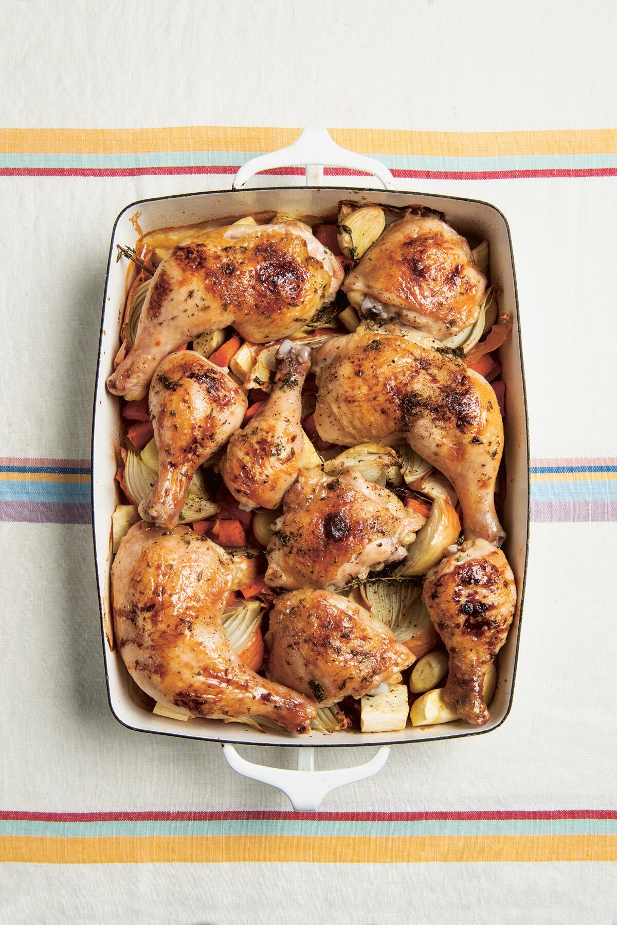 A pan of roast chicken parts with honey, thyme and root vegetables.