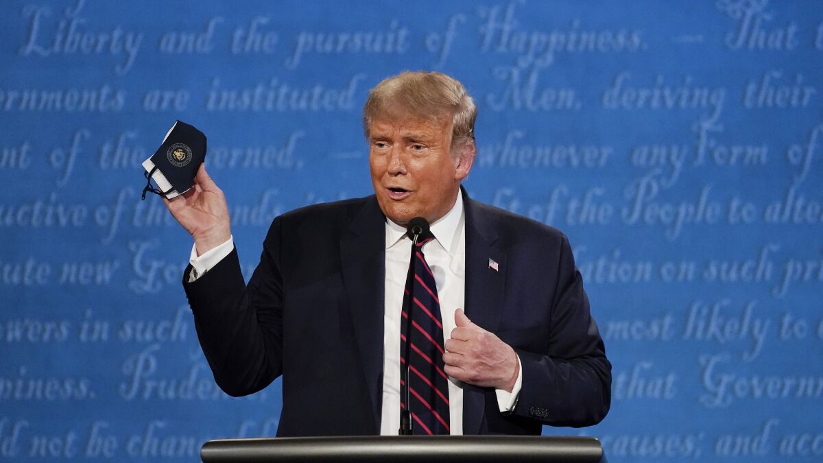 President Trump holds up his face mask during the first presidential debate earlier this week.