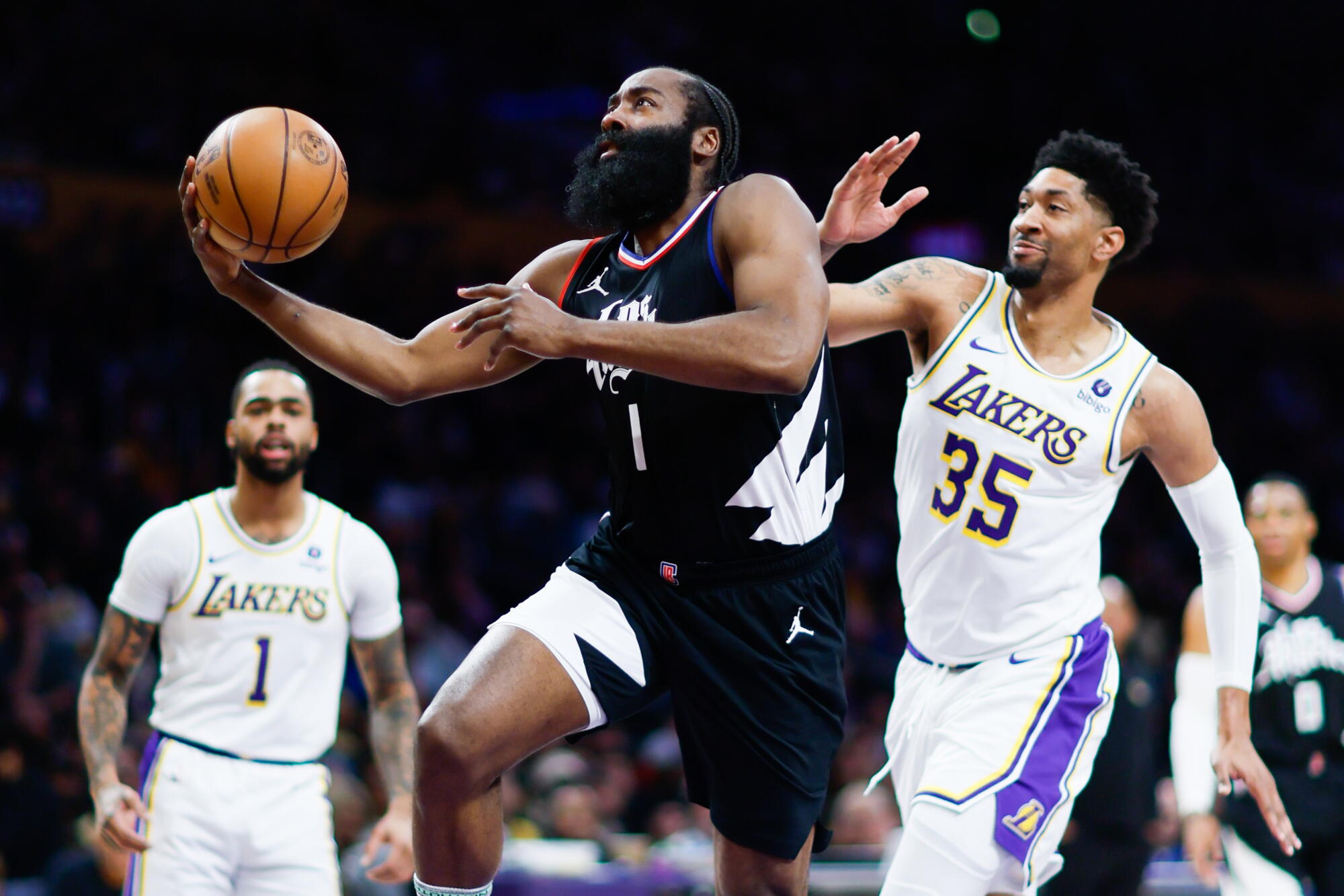 Clippers guardı James Harden (1 numara), Lakers'ın forveti Christian Wood'un yanından potaya doğru ilerliyor.