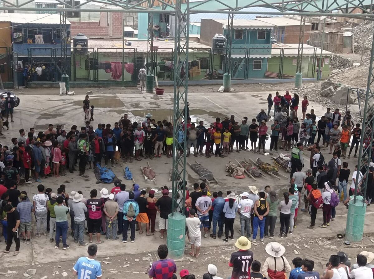 Residents standing around bodies of people who died in landslides in Camana, Peru