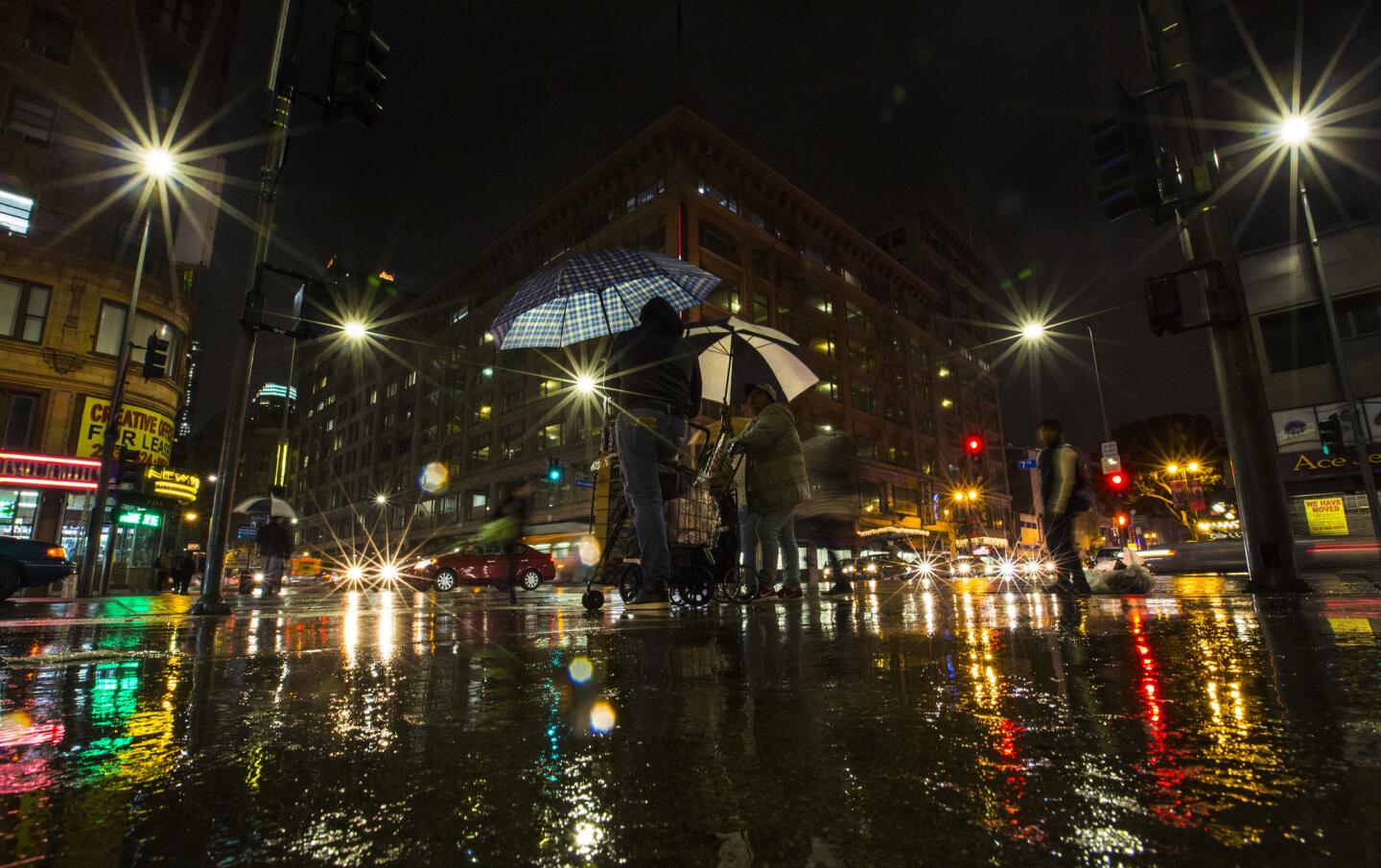 Umbrellas come out as a steady rain falls at 7th Street and Broadway in downtown Los Angeles on Thursday night.
