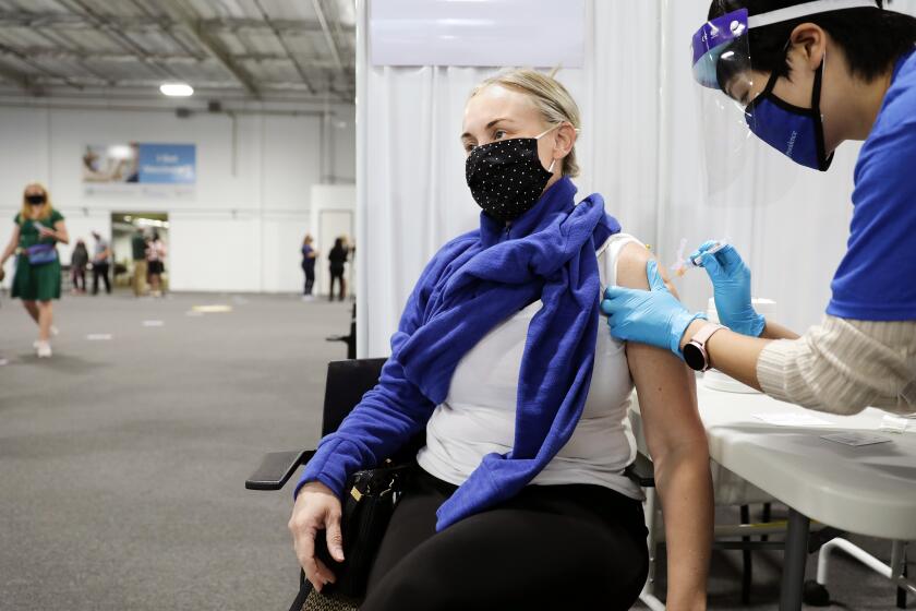 SANTA ANA-CA-APRIL 22, 2021: Juliet Schade, 46, of Santa Ana, receives a Moderna vaccine by nurse Yajie Yang, right, at a new mass vaccination site in Orange County-the Providence Vaccine Clinic at Edwards Lifescience in Santa Ana on Thursday, April 22, 2021. (Christina House / Los Angeles Times)