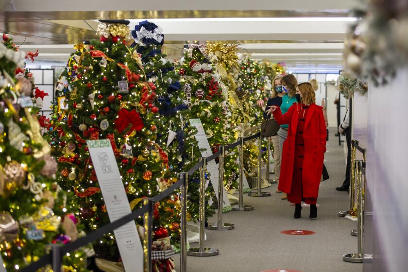 Kelsey OÕBrien, with South Coast Plaza, shows Paulette Lombardi-Fries, center, and Jenny Wedg with Travel Costa Mesa some of the 35 holiday trees decorated by regional, national and global arts institutions during a media open house on Friday, November 13.