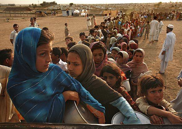 Taj Mina, 10, in blue scarf, and Mariam, in brown, line up for food at the refugee camp dubbed Little Lahore outside Swabi. Residents queue for hours for supplies in extreme heat, without water or electricity.
