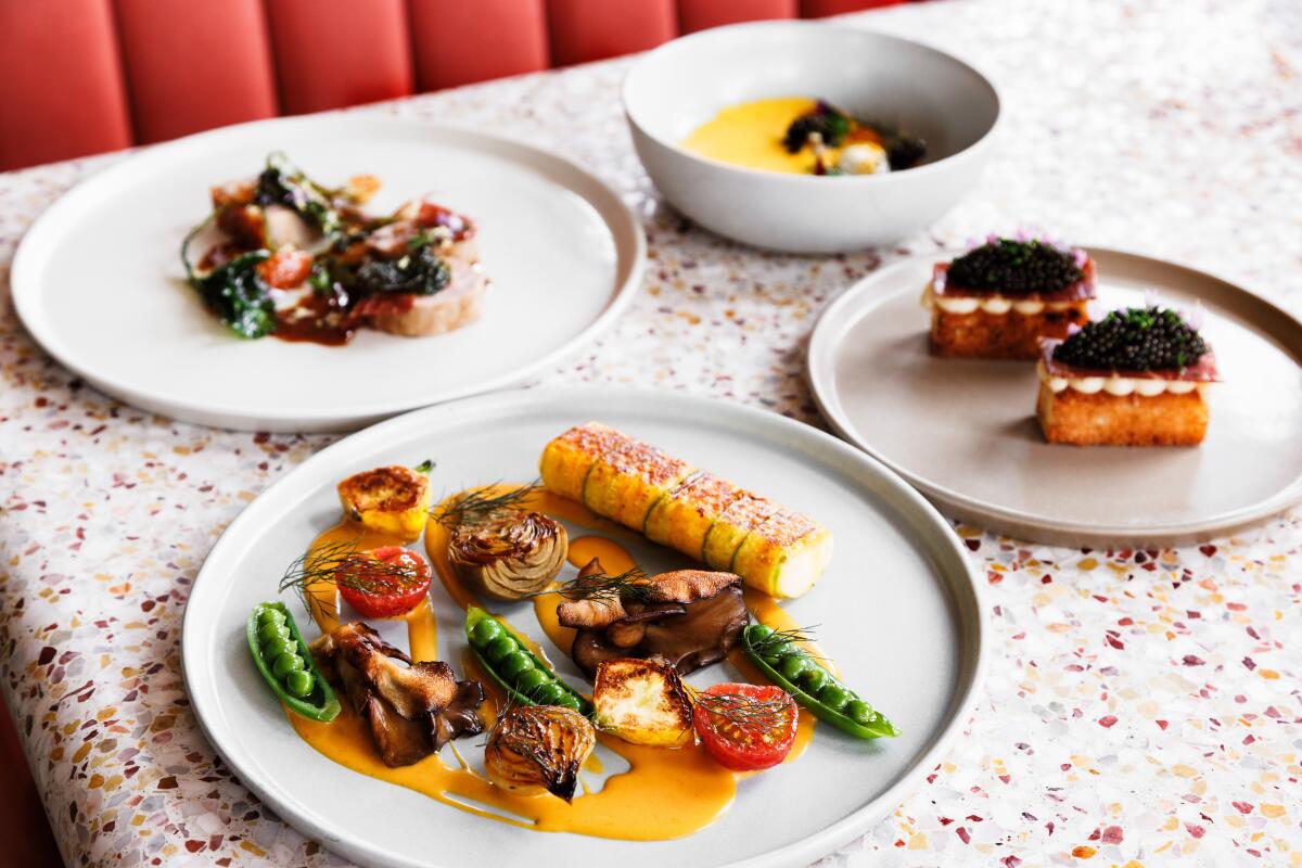 Four dishes of food on a mottled restaurant table