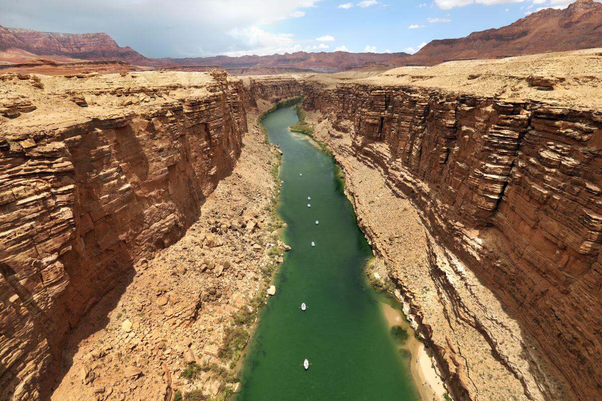 An aerial view of rafters in the green waters of a river in a canyon