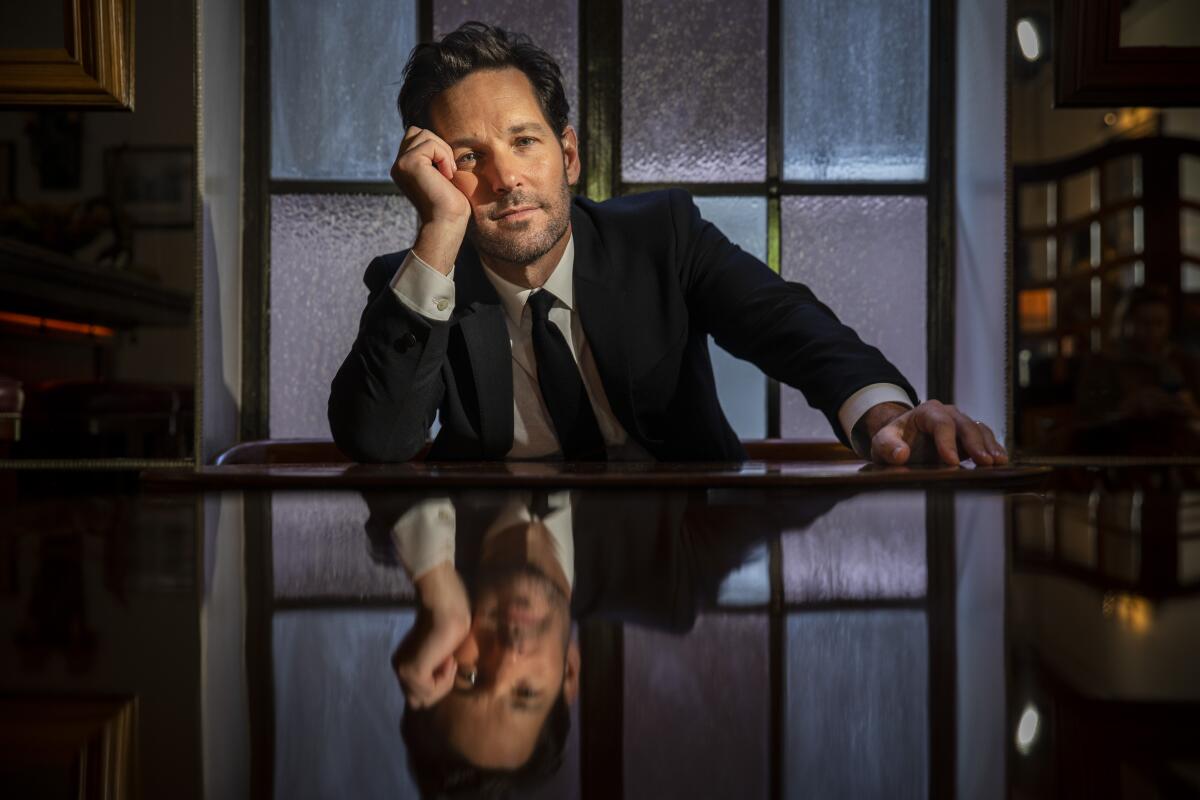 A man in a suit sitting at a table with his cheek on his hand