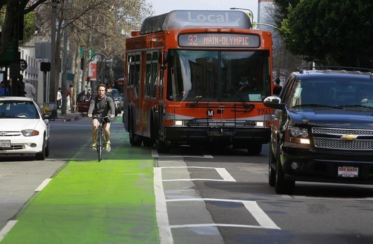 Cyclists, cars and buses pass on the green-painted bike lane in the 400 block of Spring Street in Los Angeles.