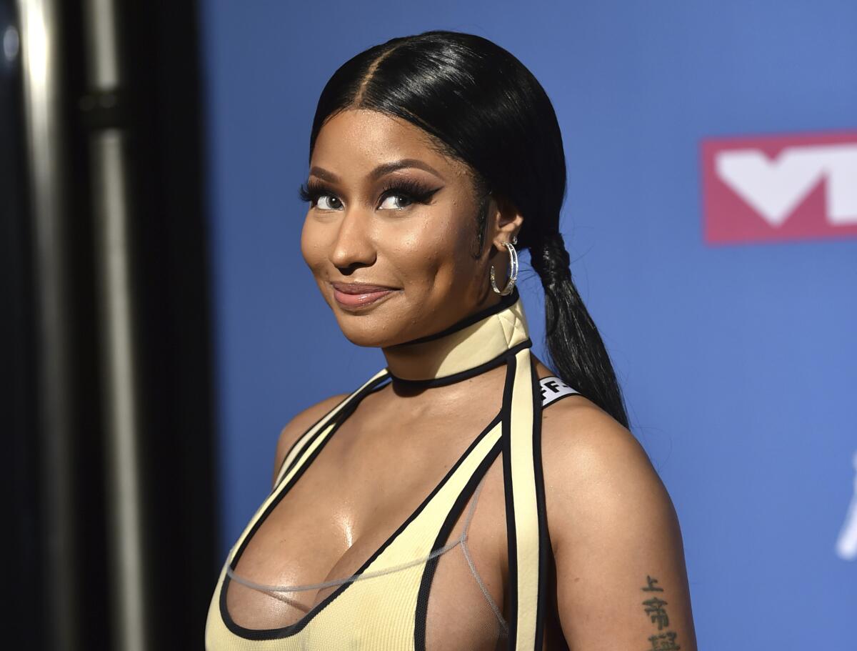 A woman wearing pigtails and a yellow top looks to the camera and smiles.