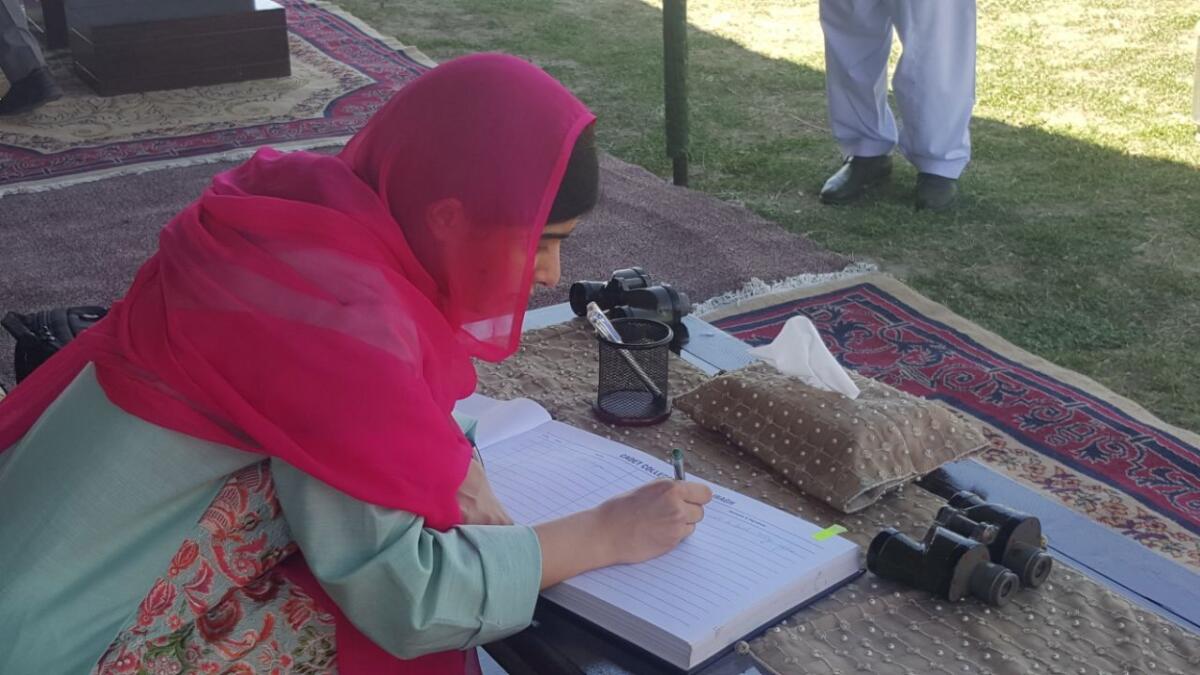 Nobel Peace Prize winner Malala Yousafzai signs a guestbook in her hometown of Mingora, Pakistan, on March 31, 2018.