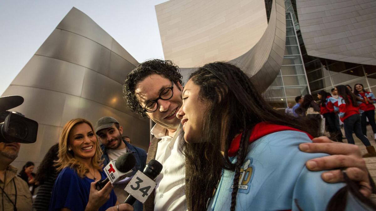 El director de la Filarmónica de Los Ángeles, Gustavo Dudamel, y la violoncelista de la Orquesta Juvenil de Los Ángeles, Karla Melgar, son entrevistados por reporteros de televisión afuera del Disney Hall en el downtown de L.A.