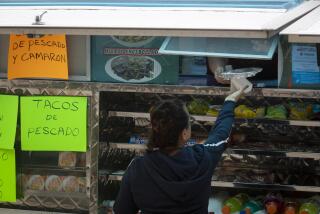 LOS ANGELES, CALIF. - MARCH 17: A woman reaches up and recieves her lunchfrom a food truck parked outside LAC USC in Los Angeles, Calif. on Tuesday, March 17, 2020. Food trucks and vendors outside LAC USC are impacted by the COVID-19 outbreack. In an effort to protect public health and safety, Federal, State, and local governments have declared a State of Emergency. With those declarations, various directives have been put in place at the local level aimed at reducing the risk of exposure and mitigating the spread of the novel Coronavirus (COVID-19). In keeping with the intent of the aforementioned policies, it is necessary to impose a temporary moratorium on street vending in the public right of way to protect Angelenos from the novel Coronavirus pandemic. Los Angeles City Attorney, with the assistance of StreetsLA, be requested to prepare and present an ordinance establishing a temporary moratorium on street vending for the length of the current local emergency, and that this ordinance include and Urgency Clause given the need for timely action on this matter. (Francine Orr / Los Angeles Times)