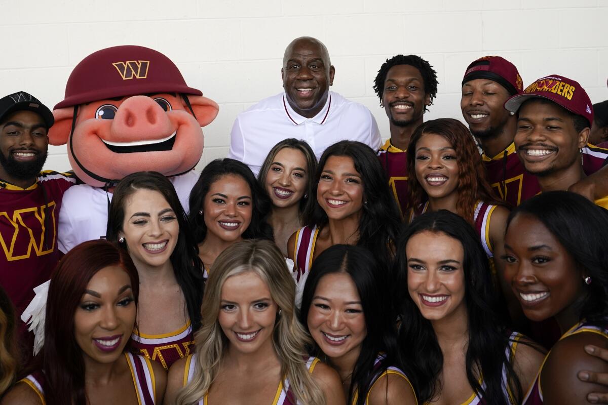 Magic Johnson, center, poses for a photo with members of the Washington Commanders' cheer squad.