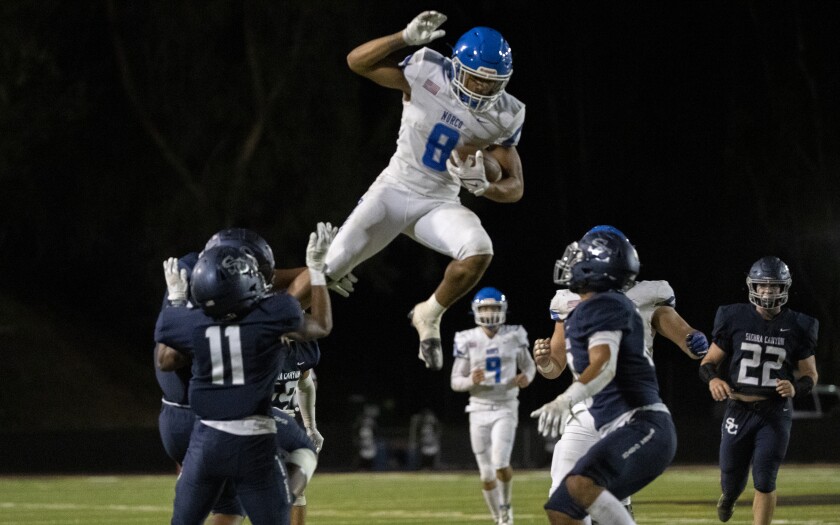Norco running back Jaydn Ott tries to leap over Sierra Canyon defenders.