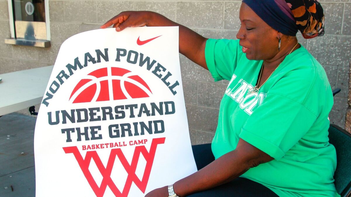 Sharon Powell, mother of Norman Powell, holds up a sign for the Norman Powell Youth Basketball Camp.