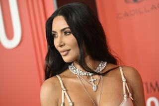 Kim Kardashian wearing a thin-strapped dress and a chunky necklace looking to her right