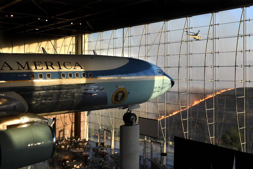 SIMI VALLEY, CALIFORNIA OCTOBER 30, 2019-President Ronald Reagan's Air Force One sits on display at the Reagan Library as an L.A. County Fire helicopter prepares to make a water drop on the Easy Fire in Simi Valley Wednesday. (Wally Skalij/Los Angerles Times)