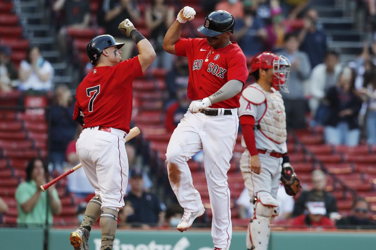 The Red Sox's Rafael Devers celebrates his home run with Christian Vazquez (7) as Angels catcher Kurt Suzuki looks on.