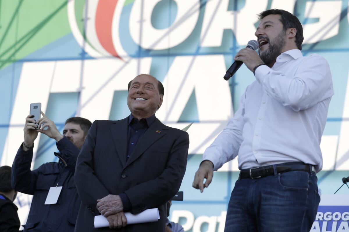 FILE - The League leader Matteo Salvini, right, is flanked by Silvio Berlusconi as he addresses a rally in Rome, on Oct. 19, 2019. The ink had barely dried on the presidential decree putting a premature end to Parliament after Italian Premier Mario Draghi's government collapsed, but politicians, including coalition allies who helped topple him, were already rushing into campaign mode on Friday. Perhaps the quickest was Matteo Salvini, the right-wing leader, who teamed up with former Premier Silvio Berlusconi to desert a confidence vote that Draghi sought this week to revive his struggling 17-month-old coalition, (AP Photo/Andrew Medichini)
