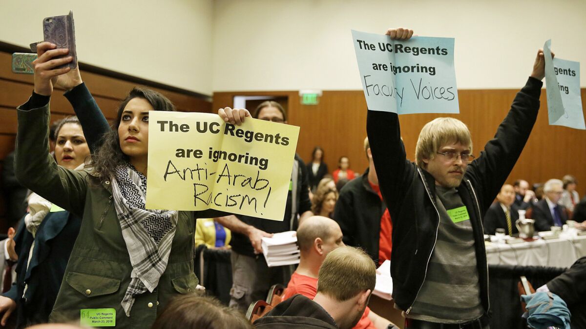 Students hold up protest signs at a UC Board of Regents meeting in March 2016 in San Francisco.