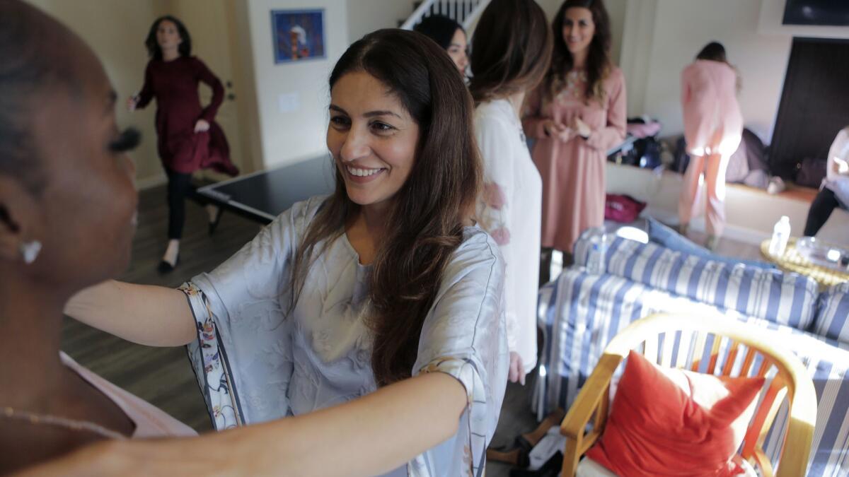 Artizara founder Sarah Ansari, center, adjust a model's clothing before a fashion show at her Encinitas home on Sunday. Her company specializes in selling modest, Islamic art-inspired fashion and lifestyle items.